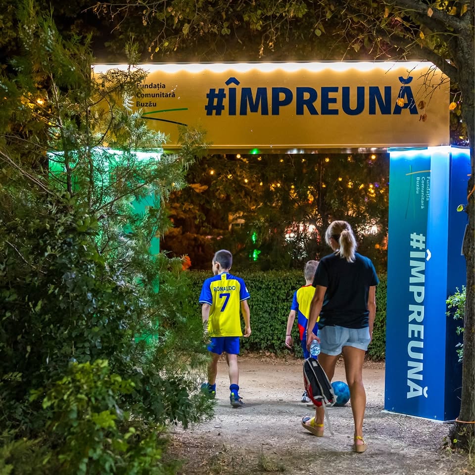 Oameni intră prin poarta #ÎMPREUNĂ a Fundației Comunitare Buzău.